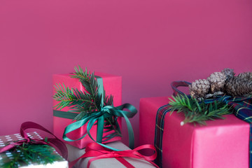 Different holiday gifts with bows on pink background, top view, copy space.
