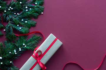 Christmas composition. Christmas gift, pine cones, fir branches on red background. Top view, copy space.