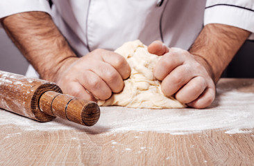 male chef kneads the dough