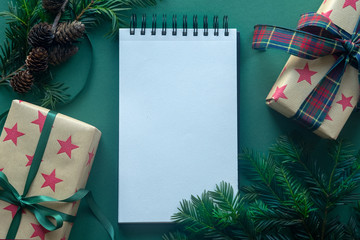 Christmas background with gift boxes and blank notebook, copy space. Template for new year goals. Flat lay, top view.