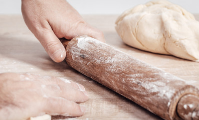 male cook rolls out dough with rolling pin
