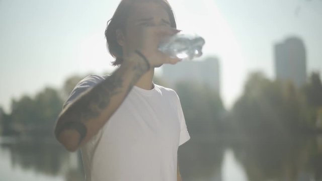 Handsome male drinks water from bottle