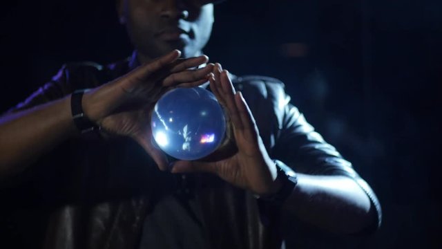 4K Magician holds the ball between his thumbs and turning it showing the light play