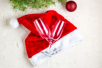 Fototapeta na wymiar wo champagne glasses with Christmas decorations, christmas tree and Santa hat