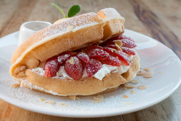 Close up of vanilla ice cream with waffle and fresh strawberry on wood table background