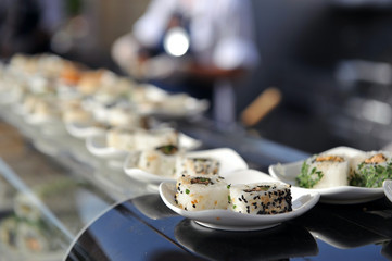 Kinds of sushi on narrow white plates.