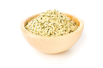 Heap of raw, organic hemp seeds in wooden bowl over white