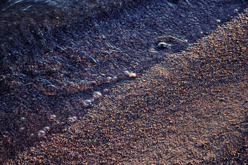 Small waves wash up along a sandy beach.