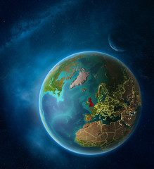 Planet Earth with highlighted United Kingdom in space with Moon and Milky Way. Visible city lights and country borders.