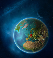 Planet Earth with highlighted Germany in space with Moon and Milky Way. Visible city lights and country borders.