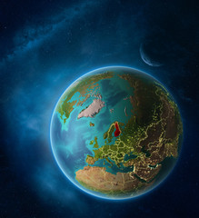 Planet Earth with highlighted Finland in space with Moon and Milky Way. Visible city lights and country borders.