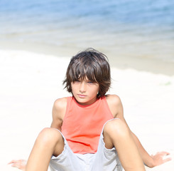 background. handsome guy in orange t-shirt is sitting on the beach