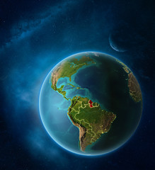 Planet Earth with highlighted Guyana in space with Moon and Milky Way. Visible city lights and country borders.