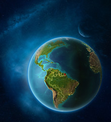 Planet Earth with highlighted French Guiana in space with Moon and Milky Way. Visible city lights and country borders.