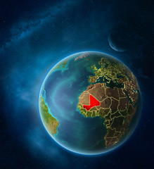 Planet Earth with highlighted Mali in space with Moon and Milky Way. Visible city lights and country borders.