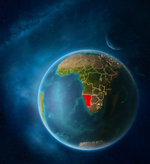 Planet Earth with highlighted Namibia in space with Moon and Milky Way. Visible city lights and country borders.