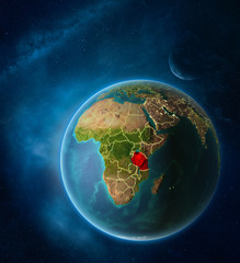 Planet Earth with highlighted Tanzania in space with Moon and Milky Way. Visible city lights and country borders.
