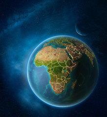Fototapeta premium Planet Earth with highlighted Rwanda in space with Moon and Milky Way. Visible city lights and country borders.
