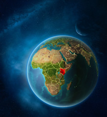 Planet Earth with highlighted Kenya in space with Moon and Milky Way. Visible city lights and country borders.