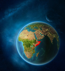 Planet Earth with highlighted Somalia in space with Moon and Milky Way. Visible city lights and country borders.