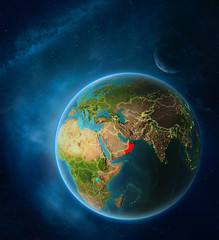 Planet Earth with highlighted Oman in space with Moon and Milky Way. Visible city lights and country borders.