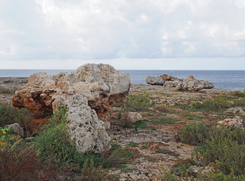 Rough coastal terrain with scattered large boulders on rocky cliff tops typical of menorca spain