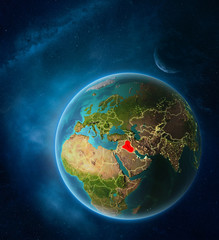 Planet Earth with highlighted Iraq in space with Moon and Milky Way. Visible city lights and country borders.