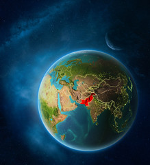 Planet Earth with highlighted Pakistan in space with Moon and Milky Way. Visible city lights and country borders.