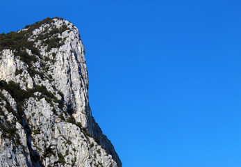 Vertical mountain cliff against clear blue sky in summer