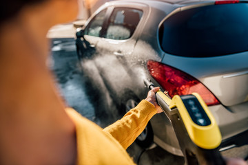 Woman washing her car with pressure washer