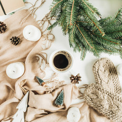 Christmas / New Year composition. Coffee mug, wreath frame of fir branches, knitted mittens, beige blanket and decorations. Flat lay, top view.