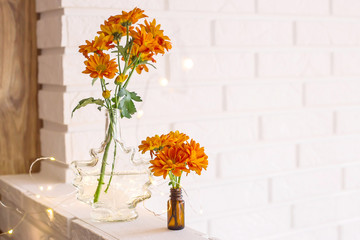 Fototapeta na wymiar Large and small bouquets of orange chrysanthemums in vases in the autumn bright home interior. Comfort and beauty at home
