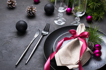 Christmas or New Year table setting with christmas pine branches, holiday decorations knife, fork ,ribbon and plate. Menu concept on dark background