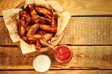 top view of delicious fried chicken wings with sauces on an old wooden table