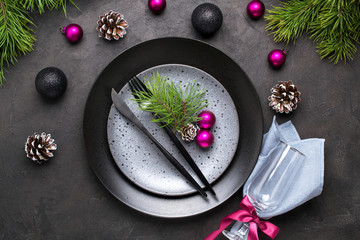 Christmas menu concept . Flat lay with Xmas decorations, dark plates, fork and knife set with napkin.