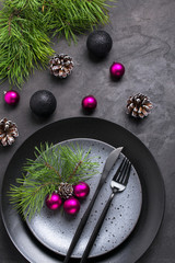 Christmas menu concept . Flat lay with Xmas decorations, dark plates, fork and knife set with napkin. Copy space