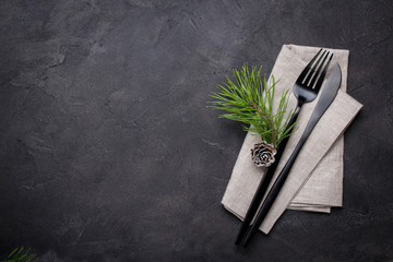 Christmas menu concept . Flat lay with Xmas decorations and pine cones, dark  fork and knife set with napkin. Copy space