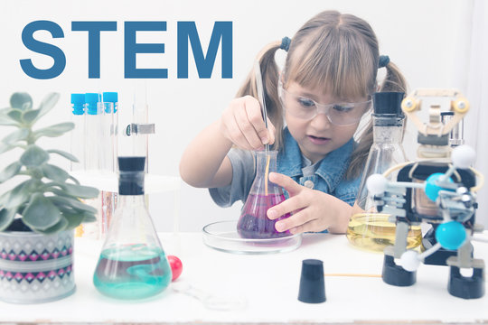 A girl child collect molecules and conduct chemical experiments. On the table is a robot. STEM education. Science and technology. Science school, Workshop.