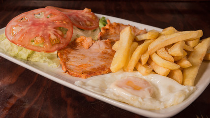 Fried egg widh marinated loin, tomato salad and chips