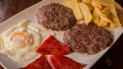 Fried egg with hamburguers, red pepper and chips