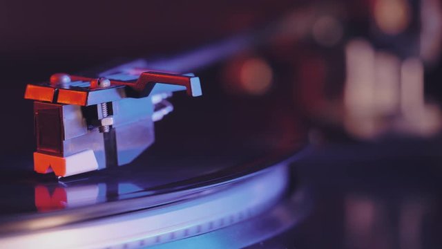 Cinemagraph Loop Vinyl Record Player. Movie of retro-styled record player spinning black record. Side view. Beautiful neon night colors. 4k.