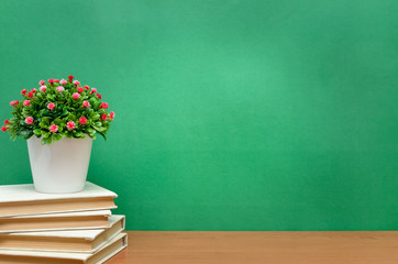 Stack of books and green plant tree on the green school board background. Back to school.
