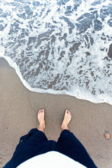 Blue waves in the sand with male feet