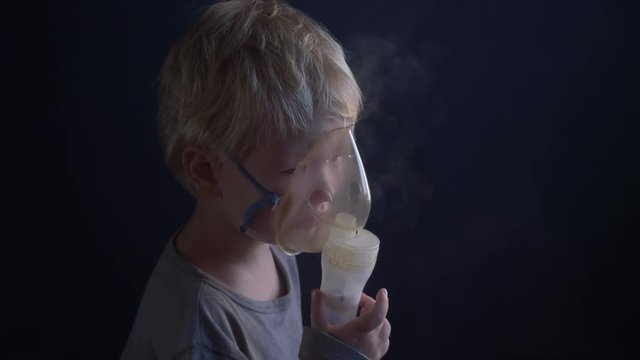 Caucasian blonde boy inhales couples containing medication from inhaler to stop coughing. Medical procedures. Inhaler. Respiratory medicine. Bronchitis, asthmatic health problem. Home treatment breath