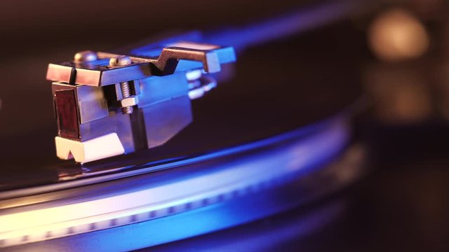 Record player turntable HD stock footage. A record player turntable with it's stylus running along a vinyl record. Neon violet light.