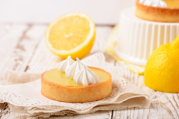 Lemon pie on the table with citrus fruits. Traditional french sweet pastry tart. Delicious, appetizing, homemade dessert with lemon curd cream. Copy space