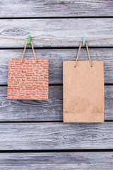 Two brown packages hang on clothespins. Kraft paper shopping bags hanging with colorful clothespegs on vintage wooden background.