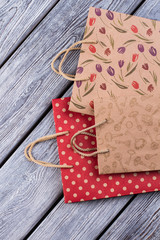 Craft paper shopping bags. Paper gift bags with different patterns on wooden background. Sale, retail and business concept.