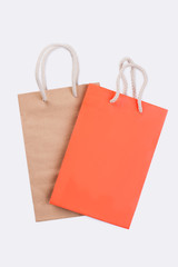 Two shopping bags on white background. Orange and brown paper bags, studio shot.