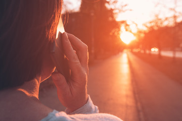 Woman talking on mobile phone on street in sunset
